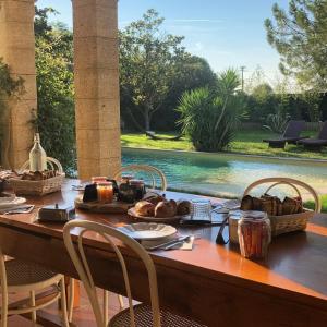 艾马尔格Le Patio, chambres d hôtes pour adultes en Camargue, possibilité de naturisme à la piscine,的一张桌子,上面有食物,放在游泳池边