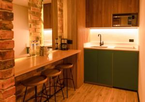 麦德林Nomada Hotel Origen的厨房配有绿色橱柜和酒吧凳子