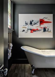 朴茨茅斯朴茨茅斯市中心酒店的带浴缸的浴室,墙上有绘画作品