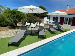 CanoFerroa Guest House的一组椅子和一把遮阳伞,位于游泳池旁