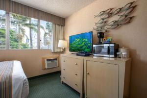 檀香山威基基阿瓜阿洛哈冲浪酒店的一间设有床铺的房间和一个带电视的梳妆台