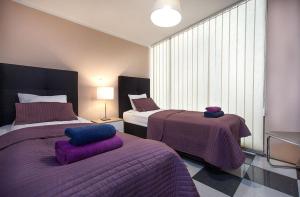 马里博尔Rooms & Apartments Banjac的一间卧室配有两张带紫色毯子的床和窗户。