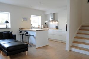 斯卡恩Skagen Apartment的厨房配有白色橱柜和黑色皮椅