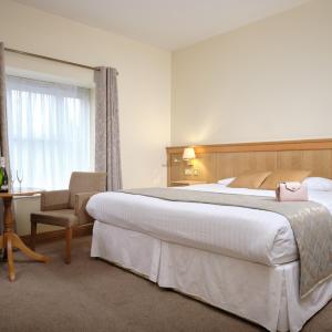 Irvinestown马洪酒店的酒店客房带一张大床和一把椅子