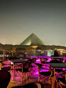 开罗MagiC Pyramids INN的一组桌子和椅子,有金字塔背景