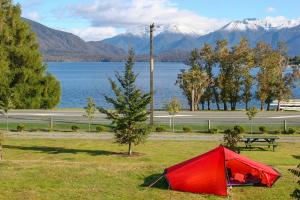 蒂阿瑙Te Anau Lakeview Holiday Park & Motels的湖边田野上的红色帐篷