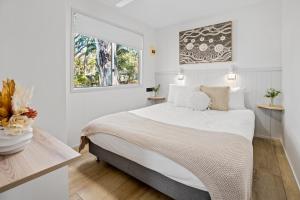 KioloaTasman Holiday Parks - Kioloa Beach的白色卧室设有一张大床和两个窗户