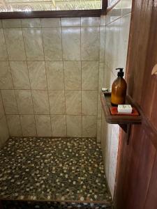 马尔多纳多港River Point Hostel的带淋浴的浴室,在架子上装有一瓶水