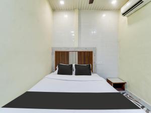 孟买OYO Hotel Metro View的卧室配有带黑色枕头的白色床