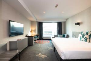 奥克兰SkyCity Hotel Auckland的一间酒店客房,配有一张大床和一台平面电视