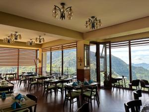 巴纳韦Banaue Grandview Hotel的餐厅配有桌椅,位于山脉的背景中