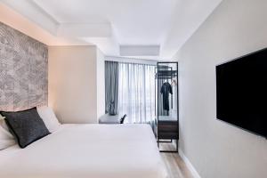 悉尼Kith Hotel Darling Harbour的配有一张床和一台平面电视的酒店客房