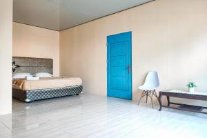 BangkoRedDoorz @ Hotel Keluarga Bangko的一间卧室配有一张床和一个蓝色的门