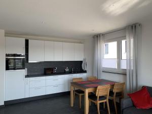 腓特烈港Holiday apartment Hildebrand Lake Constance的一间带桌椅的厨房和一间带白色橱柜的厨房