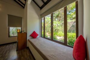 停泊岛布布别墅酒店的客房设有带红色枕头的大窗户。