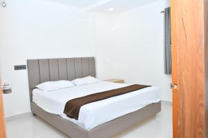 DevarkondaSWAGATH RESIDENCY的一张铺有白色床单的床和一张棕色的毯子