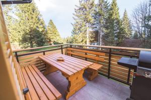 兹雷切Rogla Alpina Residence的木桌和长凳,位于树木繁茂的甲板上