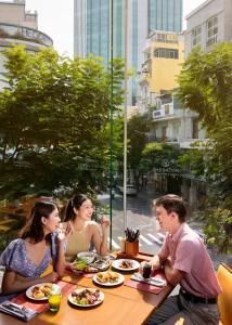 胡志明市Sheraton Saigon Grand Opera Hotel的一群坐在餐桌上吃食物的人