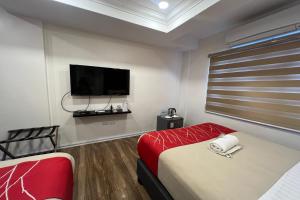 马尼拉Khotel Pasay的客房设有两张床和一台平面电视。
