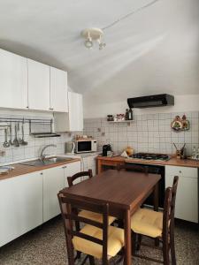 多尔切阿夸BeB I Girasoli的厨房配有白色橱柜和木桌