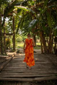 BhurkīāBardia Riverside View Park Resort的穿着橙色衣服的女子在木桥上行走