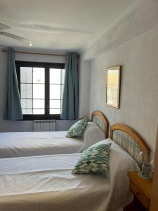 卡拉菲格拉HOSTAL RESTAURANTE CALA的卧室设有两张单人床和窗户。