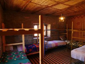 廷吉尔Auberge Hostel Traditionnel的小屋内带三张双层床的客房