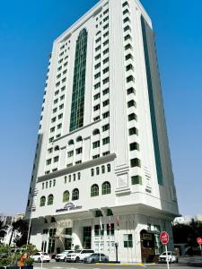 阿布扎比Howard Johnson by Wyndham Abu Dhabi Downtown的一座高大的白色建筑,前面有汽车停放