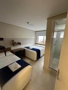 Telêmaco BorbaHotel Imperatriz的酒店客房设有两张床和淋浴。