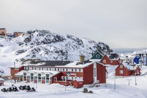 西西缪特HOTEL SØMA Sisimiut的一群人坐在雪中,站在山前