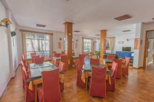 科尼尔-德拉弗龙特拉Hotel Tres Jotas Conil的用餐室配有桌子和红色椅子