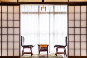东伊豆町Izu atagawa Yubana mankai -Adult Only-的窗前的两把椅子和一张桌子