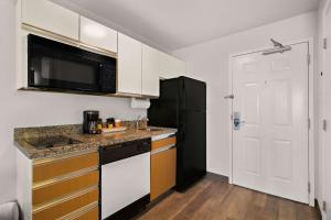 米德瓦尔MainStay Suites Salt Lake City Fort Union的厨房配有白色橱柜和黑色冰箱。