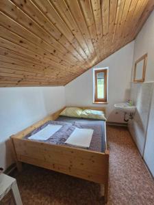 KrivčevoČrnuški dom na Mali planini的一张位于带木制天花板的客房内的大床