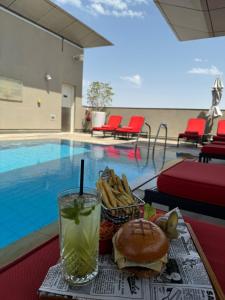 阿布扎比中央阿尔曼哈尔罗塔纳酒店的一个带三明治和饮料的托盘,在游泳池边