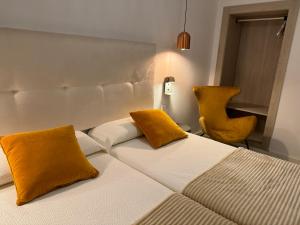 圣安东尼奥Aparthotel Boutique Poniente Playa的一间卧室配有一张带黄色枕头和椅子的床