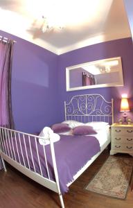 华沙Chmielna Guest House的紫色卧室配有一张床和镜子