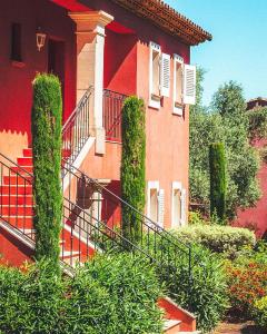 圣特罗佩拉斯特拉加勒庄园酒店的一座红色的建筑,有楼梯和灌木丛