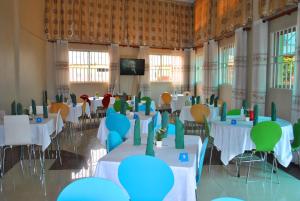 坎帕拉Pearl Highway Hotel Kibuye Kampala的一个带桌椅和电视的宴会厅