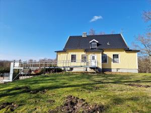 瑟尔沃斯堡Large and spacious house in Norje, Blekinge的绿色田野上黑色屋顶的黄色房子