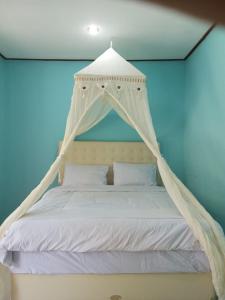 RiungRIUNG LALONG TERONG Guest House的一间卧室配有一张带天蓬的白色床