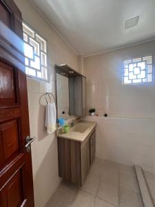 蒙巴萨SPACIOUS STUDIO IN NYALI with AC opposite voyager resort RITZ APARTMENT的一间带水槽和镜子的浴室以及窗户。