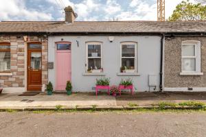 都柏林Cozy room in Stoneybatter, Dublin的白色的房子,有粉红色的门和两个粉红色的长椅