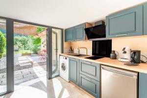 阿普特Maison Marvic, Le Laurier T2的厨房配有蓝色橱柜、洗衣机和烘干机