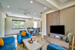 坎多林Premium 2BHK Apartment with pool at Candolim Beach的客厅配有蓝色椅子和电视