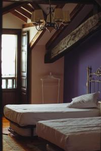 CerrazoHotel Palacio La Casona de Cerrazo的卧室设有两张床铺和紫色墙壁