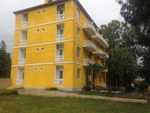 乌雷基Ureki - Evkalipt的黄色的建筑,设有白色的阳台和树木