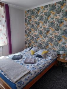 托伦Apartament LORD的一间卧室配有一张带花卉壁纸的床