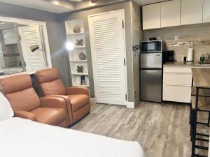 北迈阿密海滩Harmonious Suites的一间卧室配有一张床和一把椅子,一间厨房