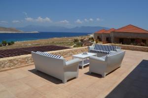 哈尔基岛Villa Blu Majestic beach villa的一个带两把椅子和一张桌子的庭院和大海